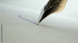 Close up of a quill pen writing a letter with blue ink. Calligraphy, handwriting