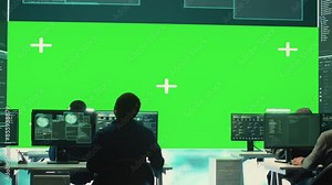 Team of governmental hackers look at green screen in high tech agency office, working together on hacking database systems for cyberwarfare activity. Experts conducting illegal scams. Camera A.