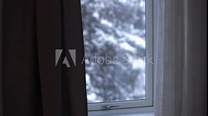 it's snowing outside the window snowflakes are slowly swirling outside the window a sad picture behind the curtain a snowy landscape snow fell it got cold winter has come sadness and withering