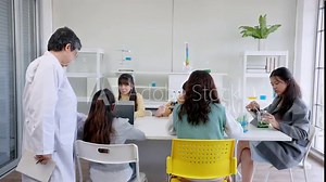 Primary school science class, schoolchildren experimenting with mixing solutions with test tubes, senior science teacher Checking student experiment results which was recorded on the laptop computer