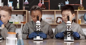 Lesson in a modern school, kids look at microscopes and communicate in a chemistry lesson, the process of teaching children and biology in a modern school.
