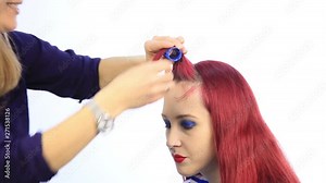 female stylist creating perfect hairstyle with large curls for young redhead woman