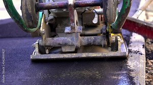 Vibratory asphalt paving machine on the sidewalk filmed close-up.Road works,pavement repair,hard work.Video clip.