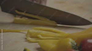 Cutting Yellow Bell Pepper into Thin Strips for Cooking on a Wooden Board