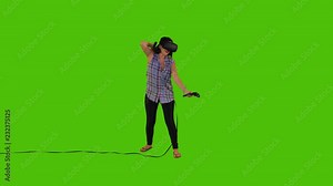 Shooting arrows happily using a longbow in a VR video game by a young woman over a green screen, casual look, long shot. Stock Video