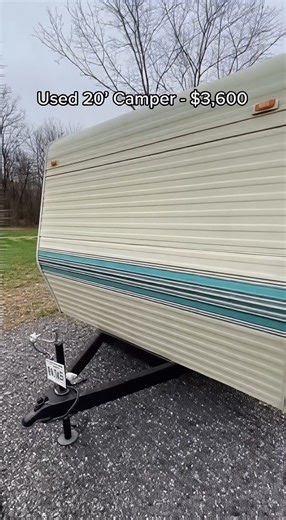 20-foot camper listed for $3,600. The footage focuses only on the camper itself, without showing any people or faces. From the outside, the camper shows visible age with faded siding and worn details, but the unit sits level, body panels appear straight, and windows are intact. Inside, the camera begins at the entry to check the flooring, which feels firm with no visible soft spots. The interior layout is basic and compact, offering functional space for sleeping and movement. Walls and ceiling s
