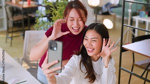 Happy group of creative asian workers taking a selfie at the office using a smartphone taking a self-portrait in a modern business office. Employee Engagement and Corporate Culture.