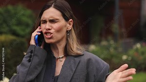 Close up of annoyed irritated young woman with an angry face have call talk looking furious, mad and feeling frustrated standing on the street. Yelling brunette girl expressions and emotions. Oh no.