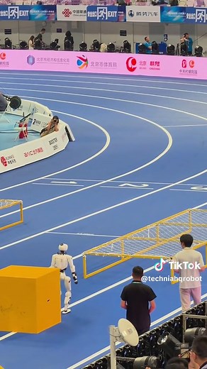 Humanoid robots are learning to move through obstacles that force full-body coordination. This footage comes from the 100m obstacle final at the 2026 World Humanoid Robot Games in Beijing. The robot climbs onto a large platform using its arms and legs. It gets back onto the track. Then it lowers its entire body and crawls under a low net tunnel. The full 100m course included 10 obstacles such as ramps, hurdles, narrow passages, an S-shaped bridge, stairs, a hand-supported platform and a crawl tu