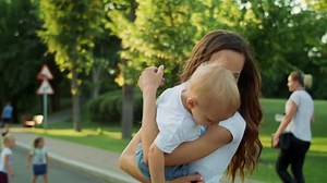 Madre cogiendo a su hijo de la mano afuera, mujer y niño pequeño dando la vuelta en la calle