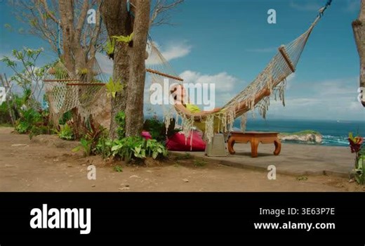 Peaceful woman napping in hammock between trees at a scenic cliffside destination in Nusa Penida Stock Video Footage - Alamy