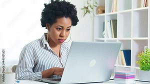 Portrait of African American young woman working on laptop remotely. Black girl student is studying online using a computer. Female freelancer. 4K.