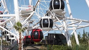 Close up red and white ferris wheel booths spins in amusement park against blue sky. great day out for whole family or friends. Fear of heights and fear on ferris wheel.