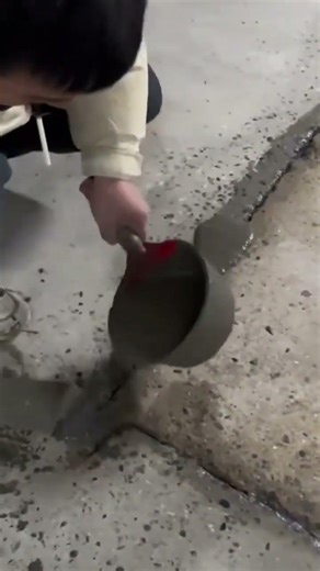 filling the cracked concrete floor precisely using wet cement and a metal hand trowel tool today