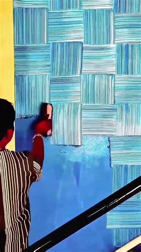 Applying a bright blue textured paint to a wall using a patterned roller to create a woven design