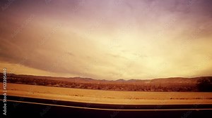 A dramatic fish eye view looking out at an open desert from a moving car.