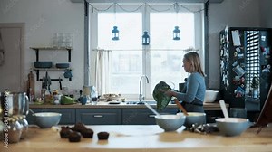 Young beautiful woman washing the bowl after baking the cupcakes. Blonde female cleaning the kitchen after cooking.