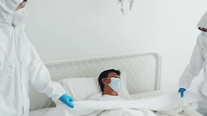 Medical team wearing PPE suits taking care of elderly patients infected with influenza regrets, covers the body of the patient died of the infection in the lungs died on the bed during the quarantine.