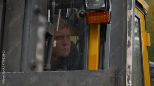 Excavator machine operator looking from the open window. Excavator machine operator watching the pouring rain. Excavator machine operator deals with the ore material extraction at the mine.