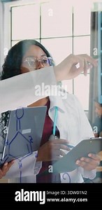 Handsome high-skilled bearded doctor together with cvalified african american female work partner standing near glass board with patients x-ray image and consulting about getted results and further treatment Stock Video Footage - Alamy