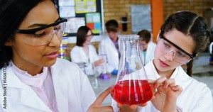School girls experimenting with chemical in laboratory at school