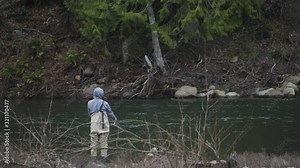Male in waders alone fishing peacefully casting pole lure on river water bank on sandy river in pacific northwest oregon wide angle in slow motion