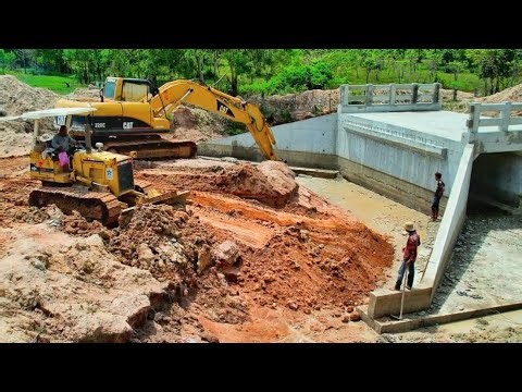 Clearing soil to bury the bridge over the canal is processed by two excavators and one bulldozer.