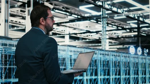Data center software developer writing code for resource optimization using laptop program. Worker walking in server hub, using programming script on notebook to upgrade IT infrastructure, camera A