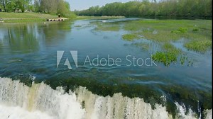 Aerial establishing view of Vimba fish (Vimba Vimba) jumping over the widest waterfall in Europe, Venta river waterfall (Ventas rumba), Kuldiga, sunny spring day, slow motion drone shot moving back Stock Video