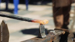 A Blacksmith at the Anvil Using a Hardy Cut Off Tool for Cutting Metal Bar. The blacksmith manually forging the molten metal on the anvil in smithy with spark fireworks