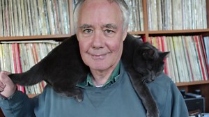 This man dresses with cat on his neck.