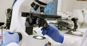Male doctor using microscope in laboratory. Using a microscope to examine the patients blood health condition. Medical device. Examining blood under the high-tech microscope equipment.
