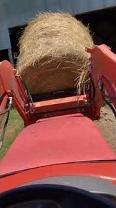 Putting round rolls of hay in the barn￼