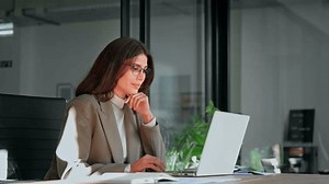 Middle age European business woman CEO using laptop application for work at table workspace in office. Smiling Latin Hispanic mature adult professional businesswoman using pc digital computer. Banner