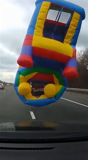 Inflatable Bounce House Explodes Open on Highway, Sending Traffic Into Shock February 14, 2026 — Drivers on a busy interstate were left stunned when a large inflatable bounce house suddenly burst open on the back of a moving pickup truck, nearly causing a chain-reaction crash. Dash cam footage shows the colorful inflatable structure strapped to a small trailer behind a red pickup. As the vehicle travels at highway speed, the wind catches part of the material. Within seconds, the bounce house vio