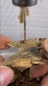 Hands using drill bit to bore hole through small agarwood piece