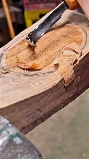 Hollowing out a wooden block surface to create a circular shape using a sharp manual adze tool