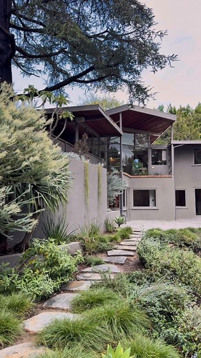 R.M. Schindler, Architect The Lechner House, 1949 Los Angeles Historic-Cultural Monument No. 1024 Hidden behind private gates, one of Schindler’s largest and most celebrated mid-century modern homes unfolds in a dramatic V shape across lush, park-like grounds—a serene setting that feels both expansive and deeply private. Inspired by Native American cave dwellings, a geometric fireplace anchors the composition, and walls of glass allow the interiors to open dramatically to the outdoors, framing w