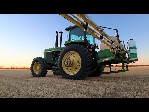 Spraying wheat field and working on John Deere 4455