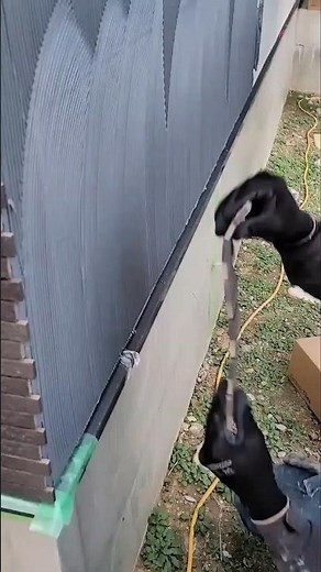 Carefully installing stacked stone tiles along a wall corner for a precise exterior finish