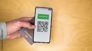 Tourist holding a passport and a Green pass certificate of vaccination. Meaningless QR code.The European Union will propose issuing a certificate called a Digital Green Pass