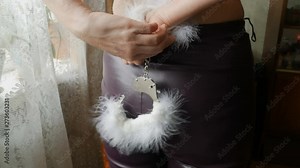 girl in leather pants trying to unfasten and remove the handcuffs