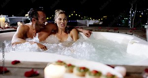 Happy couple, hot tub and night on romantic date together on valentines day or anniversary outdoors. Man and woman in relationship smiling for late romance vacation, getaway or relaxation in jacuzzi