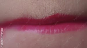 Unrecognisable woman smacks lips applying red lipstick on mouth, white teeth, detail close up, slow motion
