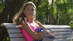 Sad lonely teenage girl sitting on bench and crying in park