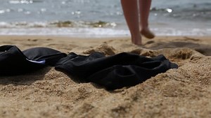 Slender young woman takes off her bikini and goes to swim in the sea