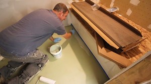 Waterproofing concrete floor...cleaned surface with shop vac and damp sponge...taped off tub and applied Hydro Ban to perimeter with paint brush...rolled on first coat, allowed to cure, then applied second coat...checked thickness using wet film gauge...set tile over cured Hydro Ban using Laticrete 4XLT...listen to video for details 👍🏼 | Home Repair Tutor