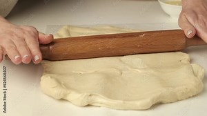 Pastry chef rolls out yeast dough using a rolling pin
