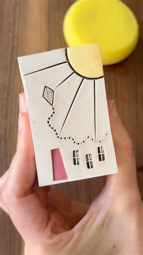 Love in Pottery on Instagram: "Katie (@snowpondceramics) is a ceramic artist who hand-builds miniature homes inspired by the quiet charm of small-town life. Her pieces feel like pocket-sized stories—simple, warm, and shaped with care. Katie showcases her delicate glazing process, using a pin dropper tool to stain the fine lines of a clay house. She brings out thoughtful details—a sun, a soaring kite, tiny windows—each one adding emotion and memory to the form. It’s pottery that speaks softly and