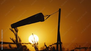 Silhouette of wind sock at sunset sky. Wind sock in countryside at sunset. Wind indicator swinging at sunset transmits information about current wind direction helps to make accurate weather forecasts